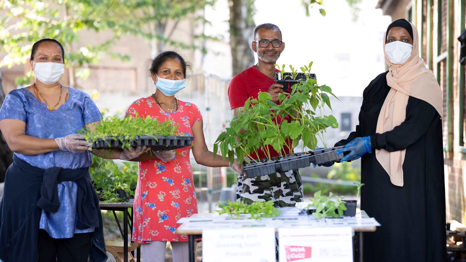 A woman in a face mask handing out plants to community members