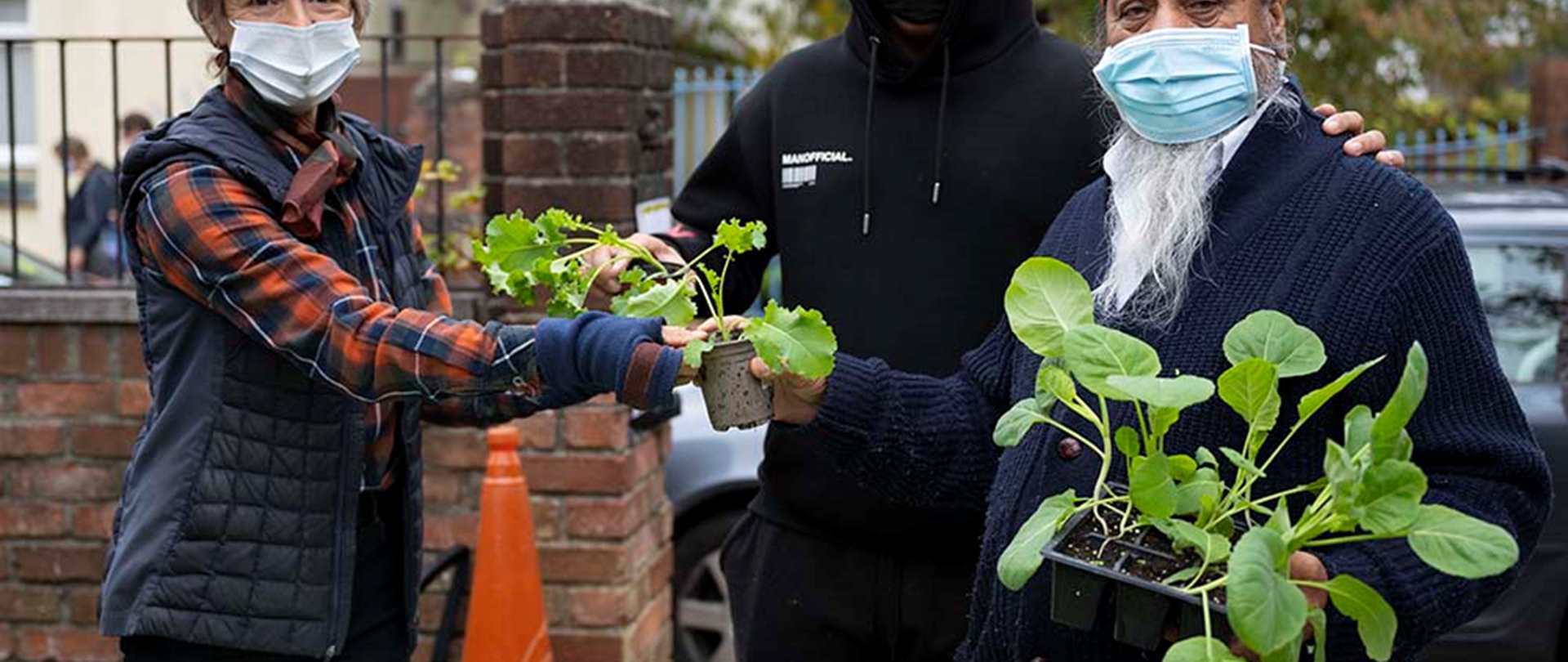 Three people sharing plants wearing Covid-19 safe masks